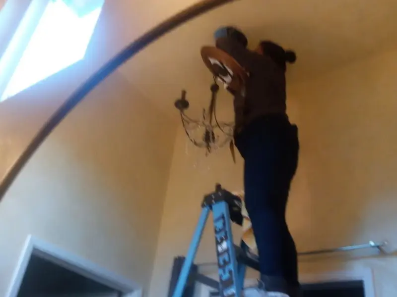 Electrician installing a chandelier in a Bolton residence